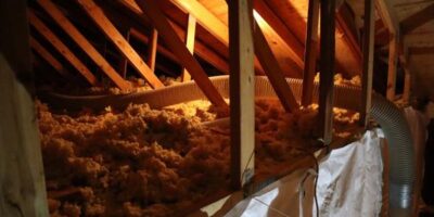 Attic with insulation and exposed wooden beams.